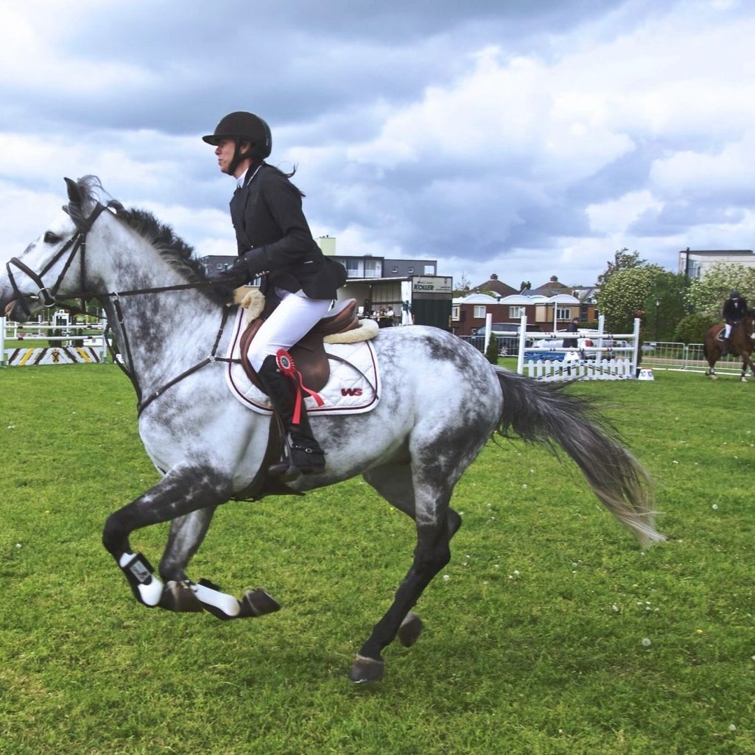 Rider on gray horse galloping in arena